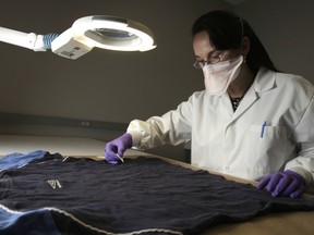 Forensic scientist Tara Brutzki from the Centre of Forensic Sciences Northern Regional Laboratory located at the Roberta Bondar building examines a shirt for evidence.