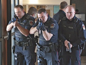 Members of the Brantford Police Better Enforcement Action Team (BEAT) move through a hallway at Laurier Brantford on Tuesday, April 30, 2013 during a critical-incident emergency simulation.  The Research and Academic Centre in downtown Brantford was locked down as police went after an active shooter in the scenario, designed to test the university's emergency procedures.