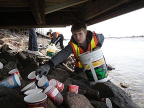 Clean North volunteer Alex Ross gathers discarded coffee cups under the boardwalk on the St. Marys River recently. The annual shoreline garbage collection was postponed for several weeks due to the snowy conditions. Over the winter, rubbish collects between the boardwalk and the river, making a mess when the snow melts in spring.