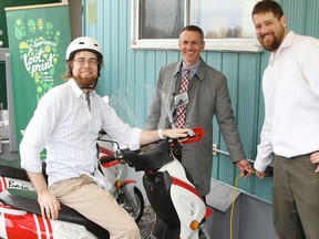 St. Lawrence College president and CEO Glenn Vollebregt, centre, helps Energy Systems Engineering Technology program students Jason Arnold, left, and Brian Fryer plug in an e-bike at the college's new charging station Tuesday morning.
Elliot Ferguson The Whig-Standard