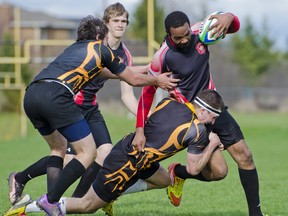 A La Salle Black Knights player tackles Queen Elizabeth Raiders’ Jamain Davis to the ground and takes a cleat to the mouth for his efforts during a Kingston Area Secondary Schools Athletic Association senior boys rugby game at La Salle on Tuesday. The Knights won 12-0. (Julia McKay/For The Whig-Standard)