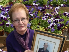 Lona Fenwick holds a picture of her husband Wayne who died of pancreatic cancer last year. Fenwick is holding a fundraiser selling pansies to fund awareness and research of pancreatic cancer. (JAMES MASTERS The Sun Times)