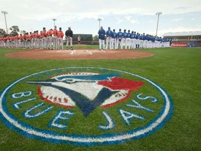 The Toronto Blue Jays and the Baltimore Orioles line up for the singing of the national anthem prior to the start of a baseball spring training game in Dunedin, Florida in February.