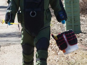 A bomb specialist deals with a suspicious package in an alley parallel to 119 Street south of 40th Avenue in Edmonton, Alta. on Friday, May. 3, 2013. After an investigation the package was discovered to be a harmless geocaching treasure. Geocaching participants use GPS units to hide and seek geocaches around the world. Amber Bracken/Edmonton Sun/QMI Agency
