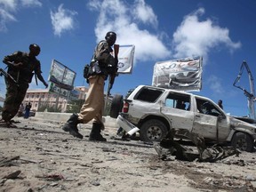 Officers stand by the remains of a wrecked car at the scene of car bomb explosion along the "Kilometre 4" road junction, south of the capital Mogadishu, May 5, 2013.  REUTERS/Feisal Omar