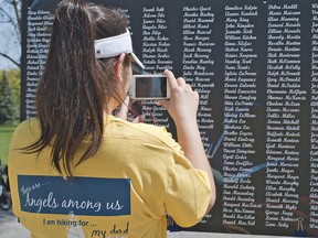 Stacy Hill of Six Nations takes a picture of her late father Clifford Hill's name on a list of people who have received end-of-life care through the Stedman Community Hospice in Brantford.  The centre's 9th annual Hike for Hospice was held Sunday, May 5, 2013 with an estimated 1,500 people taking part, working toward a fund raising goal of $200,000. (BRIAN THOMPSON Brantford Expositor)