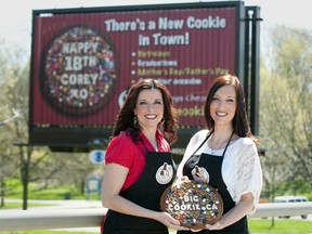 Celeste Bailey, left, and Melissa Penford-Bouk show off a giant cookie in front of a billboard the pair advertise on along Wellington Rd. The pair, both OPP dispatchers, run a chocolate business ? All Things Chocolate ? and are adding the cookiegrams to their repertoire. (CRAIG GLOVER, The London Free Press)