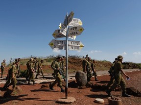 Israeli soldiers walk past signs pointing out distances to different cities at an observation point on Mount Bental in the Israeli-occupied Golan Heights May 5, 2013. (REUTERS/Baz Ratner)