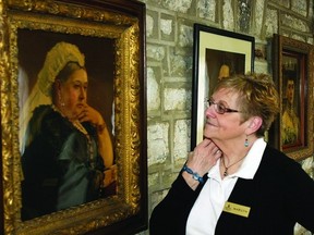 Marilyn Keable, a City Hall ambassador, looks at a portrait of Queen Victoria, which is one of several photos along “Royal Way,” a tribute to the monarchy.      ROB MOOY - KINGSTON THIS WEEK