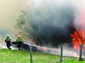 Augusta Township firefighters retreat from the edge of a bush fire that exploded in front of them just east of Highway 15 on County Rd. 26 Monday morning. The raging bush fire started when southwest winds fanned a grass fire to the east. (DARCY CHEEK The Recorder and Times)