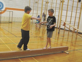 Wyatt Lange and Jaren Hermann, Grade 4 students, approach each other on a balance beam in gymnastics.