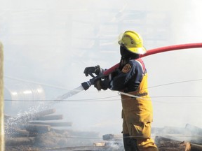 A Mayerthorpe firefighters sprays flames in the yard of a rural property about 16 kilometres north of Mayerthorpe at about 5 p.m. on Sunday, May 5.