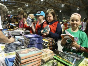 Elisabeth Mitchell, a Gr. 4 student at Alliance French Immersion Public School, bought No Shelter Here by Rob Laidlaw, during  the Festival of Trees literary event at West Ferris arena, Tuesday.