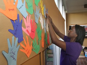 Andrea Barrow, one of the organizers of a mental health conference for high school students held Tuesday at Duncan McArthur Hall, puts handprints signed by the participating students on sheet of paper hung on a wall.
Michael Lea The Whig-Standard