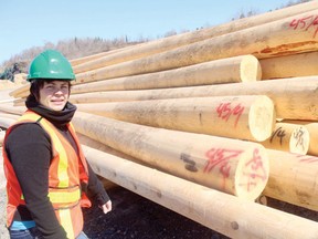 Megan Moncrief from Wincrief Forestry Products standing next to one of the many stacks of poles which are sorted by diameter and quality.