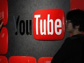 Visitors stand in front of a logo of YouTube at the YouTube Space Tokyo, operated by Google, in Tokyo Feb. 14, 2013. Reuters/Shohei Miyano