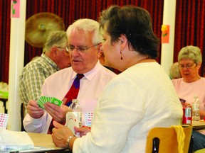 Brockville Duplicate Bridge Club founder Ed O'Reilly checks his hand as Sandra Devaney looks on during Thursday's celebratory game marking the organization's 50th anniversary. (STEVE PETTIBONE The Recorder and Times)