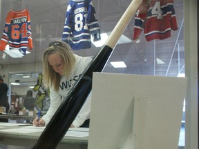 TERRY FARRELL/DAILY HERALD-TRIBUNE
Caroline Crowe takes time out of coaching the Hythe team to bid on an Jose Bautista-signed baseball bat at the ATB Investor Services 3D Charity Hockey Tournament on Saturday. This year’s tournament – the 12th annual – was the most successful to date, with in excess of $75,000 raised.