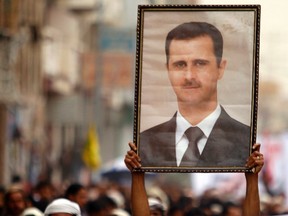 A Shi'ite anti-government protester holds up a poster of Syrian President Bashar al-Assad during a demonstration against Israeli air strikes in Syria, in Sanaa May 10, 2013. (REUTERS/Khaled Abdullah)