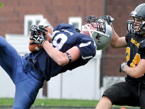 Ursuline Lancers' Zach Kaniecki, left, intercepts a pass intended for Blenheim Bobcats' Mo Ibari (24) in the second quarter of a Kent junior football game Friday at Ursuline. (MARK MALONE/The Daily News)