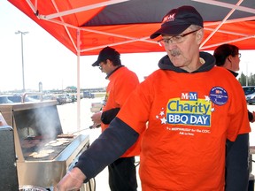 Volunteers Byron Turcotte, right, serves up a hamburger while behind him Wayne Harris cooks up some more, during the M&M Meat Shop Charity BBQ Day at the Portage la Prairie Mall Saturday. The event raised money for the Crohn's and Colitis Foundation of Canada. Turcotte's daughter has Crohn's while Harris has a connection to the food store. (CLARISE KLASSEN/PORTAGE DAILY GRAPHIC/QMI AGENCY)