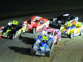 A large group of cars makes its way around turn four under a caution in the  358 Modified feature during opening night at the BOS on Saturday. (STEVE PETTIBONE The Recorder and Times)