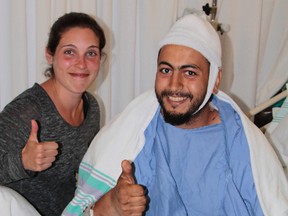 Joe Azougar, right, giving a thumbs up with girlfriend Brooke Bowerman. Azougar received 300 stitches after being attacked by a 400-pound black bear at his remote cabin near Cochrane on Saturday. (Len Gillis, QMI Agency)