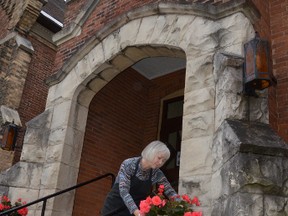 Leigh Greaves, chair of the Harmony Centre board, places flowers outside the building to greet mothers coming for tea Saturday before taking in a concert by the Georgian Bay Children’s Choir, the first such event at the community charitable organization's space.