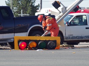 A worker disassembles a traffic light after a crash Monday morning at Second Line and North Street.