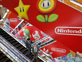 Men ride an escalator past Nintendo Co advertisements at an electronics retail store in Tokyo April 23, 2013. REUTERS/Toru Hanai