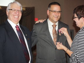Longtime member of Les Scouts in Timmins, André Aubé gets his Queen Elizabeth II Diamond Jubilee Medal pinned to his lapel by his wife Claire. Aubé was presented with the award for over 30 years of service to Les Scouts in the community. Fédération des Scouts de L’Ontario administrator Paul Gaudreau, left, was among those at the ceremony.