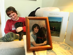 Meagan Summerton and her pug, Hamish, with photos of Jack, a black Labrador that helped the autistic woman come out of her shell, shown at their home Saturday.