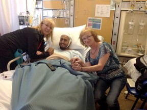 Denise Didone, left, and her sister Louise Seguin visit with Joe Azougar at Lady Minto Hospital in Cochrane. On Saturday, the sisters scared off a 400-pound black bear that was attacking Azougar. They rushed him to hospital, where he was treated for 300 stitches.