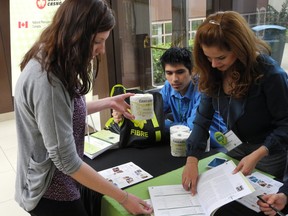 Patricia Wilbur, a Western University student gets the itinerary for the week from McGill University student, Leila Jowkarderais, after receiving a new type of toilet paper from Cascades, handed to her by University of Ottawa student, Chris Diaz-Urrutia during the FIBRE conference at the Nav Centre on Monday. 
Erika Glasberg staff photo