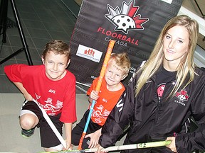 Sebastian Davis, nine, and his six-year-old brother, Elijah, pose with Team Canada women's floorball player, Tori Chapman, of Belleville, during press conference Tuesday at the Sports Centre confirming the QSC as host site of the 2016 U19 women's world championships. (Paul Svoboda/TheIntelligencer)