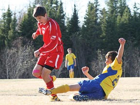 Devon Krolyk passes the ball away just before being slide tackled by a Rainy River player. Krolyk scored the lone goal in St. Thomas Aquinas’s victory over Rainy River 1-0 on Tuesday, May 14.