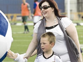 Rilan Esau, 7,  gives team mascot Kicks a high five with his mother Shalane during a salute to women in soccer held at halftime at the FC Edmonton game against the Atlanta Silverbacks at Clarke Stadium on Sunday. She was awarded the Soccer Mom of the Year award. Ian Kucerak/QMI Agency