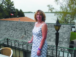 Katherine Christensen of the TIAP stands on a deck of the Gananoque Inn after announcing the island contest. Behind Christensen, just to the left of her head, is the island in the contest.
Wayne Lowrie/Gananoque Reporter