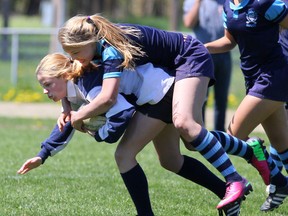 Nikki Campbell of the Walkerton District Community School Riverhawks fights off a tackle by Caroline Nicoll of the West Hill Secondary School Raiders during their BAA girls rugby match on Wednesday.