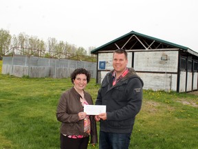 Jennifer Peart of Farm Credit Canada presents Paris Fairgrounds manager David Nash with a grant of $5,000 to put a new roof on the horse stall to the left on Tuesday. The grant money puts the Paris Agricultural Society a third of the way towards raising the $30,000 needed for the roof. MICHAEL PEELING/The Paris Star/QMI Agency