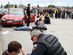 Sgt. Paul Proulx of the West Nipissing Police Service comforts Andre-Michel Rivet while other officers and paramedics tend to the "victims" of a crash at the West Nipissing Community Centre. Students from Northern Secondary School and Ecole Secondaire Catholique Franco-Cite participated in and observed the  crash scene response Thursday, May 16, 2013.