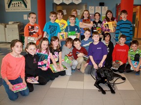 Philippe Girouard, middle, takes a break for a picture with his service dog Quintin and some of his Anicet-Morin schoolmates who helped raise money to adopt a National Service Dogs puppy and fund its first year of life. Girouard has autism and Quintin acts as a safety net for the boy when he is out and about. He said he was thrilled to offer another child the same opportunity he had with Quintin, who has rapidly become the boy’s best pal.