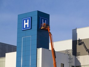 Workers put the finishing touches on signage at the new Walker Family Cancer Centre in St. Catharines, Ont., earlier this spring. The hospital is one of a number of new facilities built as public-private partnerships in recent years.