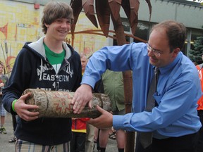 Northwestern Secondary School Grade 10 student Wade Niezen holds a freshly unearthed time capsule as teacher Stephen Fisher wipes the dirt from the logo Saturday. The time capsule was buried 25 years ago and was dug up as part of the school's 50th anniversary celebrations. (LAURA CUDWORTH, The Beacon Herald)