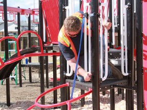 Stephane Drouin-Moreland, a member of the construction crew, put the finishing touches on the playground on Friday, May 17.