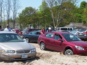 Two cars are stuck in the sand Sunday in Port Stanley in a newly opened paid parking lot. Central Elgin, which contracted the privately owned property, will reimburse motorists. (Brian King contributed photo)
