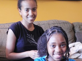 Betelhem (Beti) Girma, 17, of Ethiopia, braids the hair of Teya Knight, 8, at Knight’s home in Cornwall in preparation for an education fundraiser on Sunday. Girma has made Cornwall home and is staying in the country on a two-year student visa, but needs to raise about $12,000 to start school in September. 
Staff photo/ERIKA GLASBERG