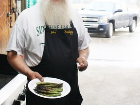 John Jaques, owner of Sunshine Asparagus, barbeques a sample of his 2011 harvest in Thamesville On. (QMI Agency file photo)