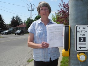 Marlene Murnaghan is being driven to distraction by the sound of these audible pedestrian signals near her home at at the intersection of St. Paul Avenue and St. George Street in Brantford. She's seen here on May 22, 2013, holding the petition she's circulating to address her concerns. (HUGO RODRIGUES Brantford Expositor)