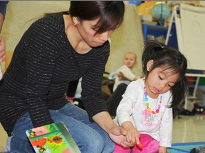 Marivel Paran reads an interactive picture book with three-year-old daughter Kai Marinelle Estillore during the Family Literacy Group for English Language Learners at St. Clement Catholic School on Wednesday.The weekly program offers games, stories, songs and crafts for parents and preschoolers looking to improve their English communication skills at home and in school. 
Elizabeth McSheffrey/Daily Herald-Tribune